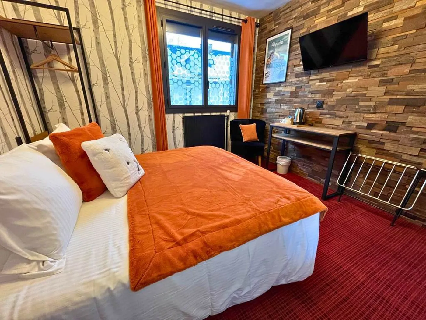 Chambre double n°3 de l'Hôtel La Rencluse avec lit Queen-size orange, mur en bois massif et papier peint forêt de bouleaux.