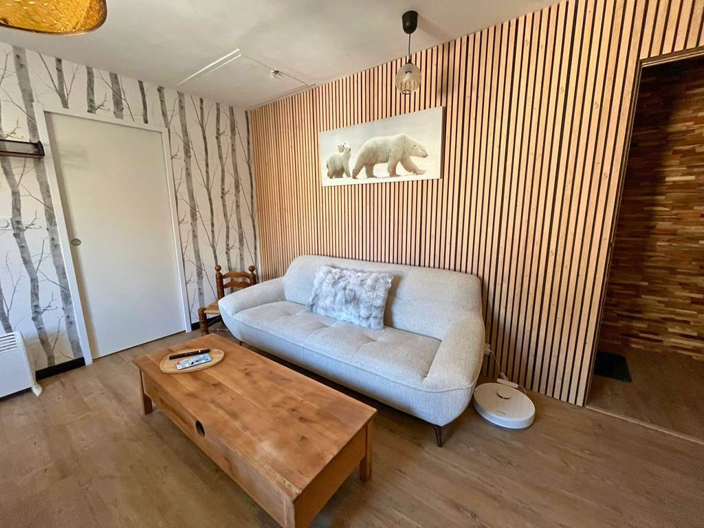 Vue du salon de l'appartement T3 avec canapé, coin repas en bois et décoration contemporaine.