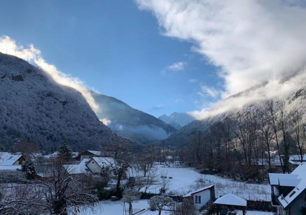 Paysage d'hiver enneigé depuis la terrasse de l'Hôtel La Rencluse, avec vue sur les pics blancs de Luchon sous un ciel bleu.