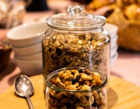 Gros plan sur des bocaux en verre remplis de délicieux cookies aux pépites de chocolat, granola maison et fruits secs, servis au buffet du petit-déjeuner gourmand de l'Hôtel La Rencluse à Luchon.