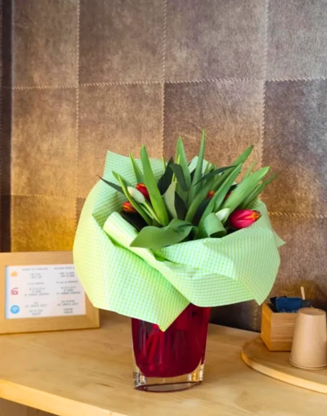 Bouquet de tulipes rouges et jaunes dans un vase sur le comptoir d'accueil, option personnalisée pour les clients de l'Hôtel La Rencluse.