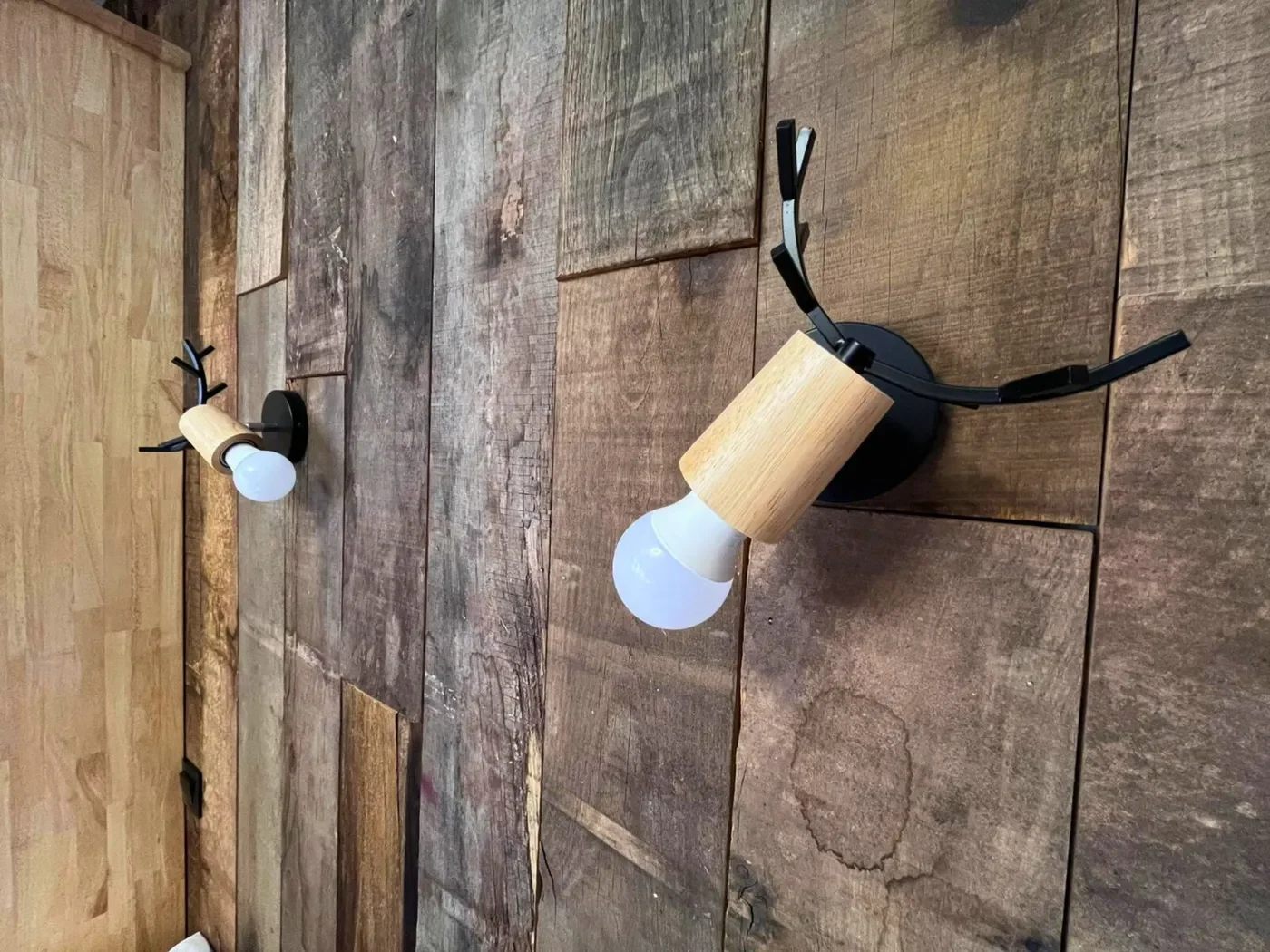 Détail des luminaires insolites en forme de bois de cerf fixés sur le mur en bois massif de la chambre n°2.