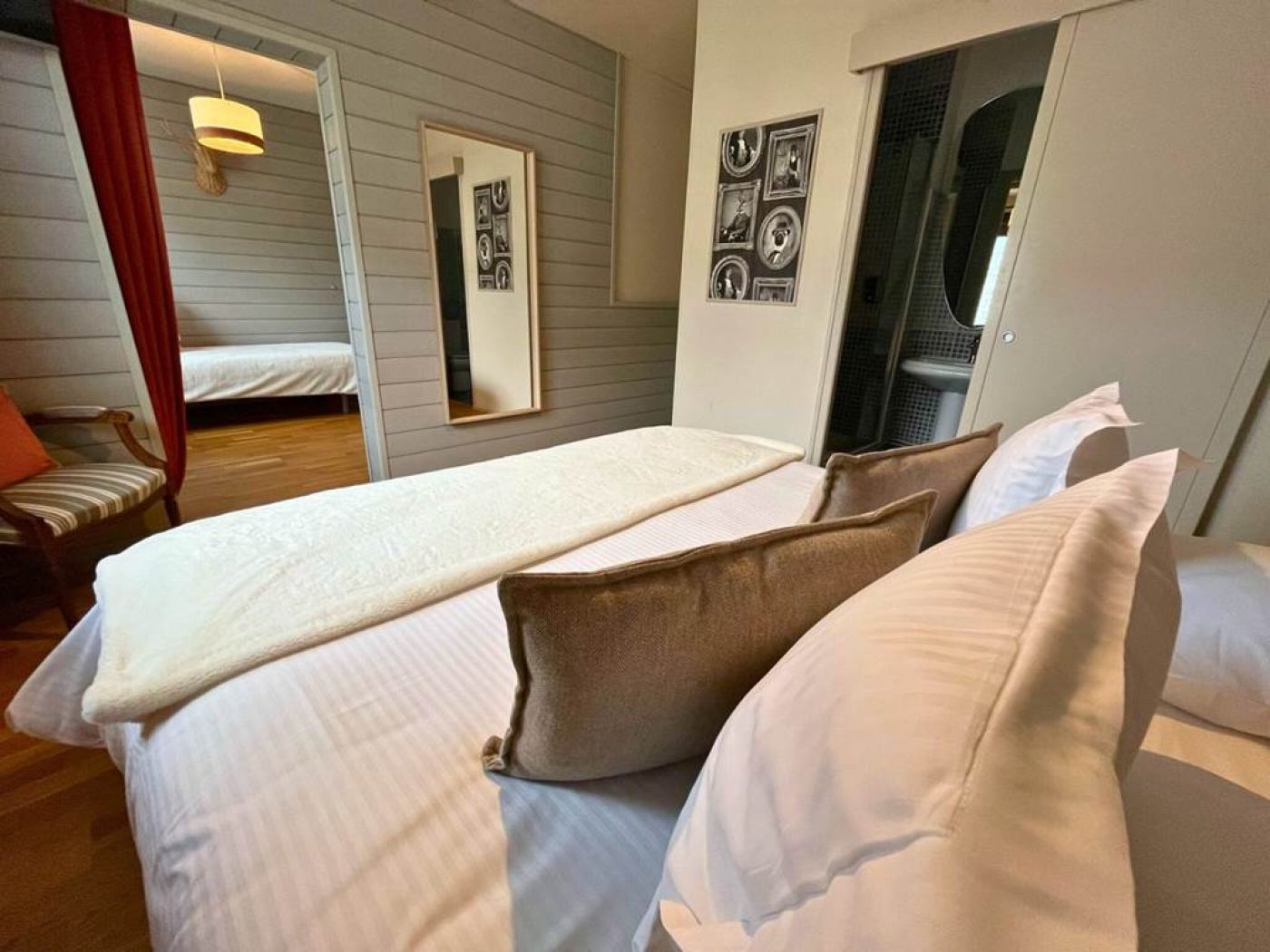 Côté gauche du lit de la chambre 4 montrant les cadres décoratifs "esprit montagne" et l'accès à la salle de bain.