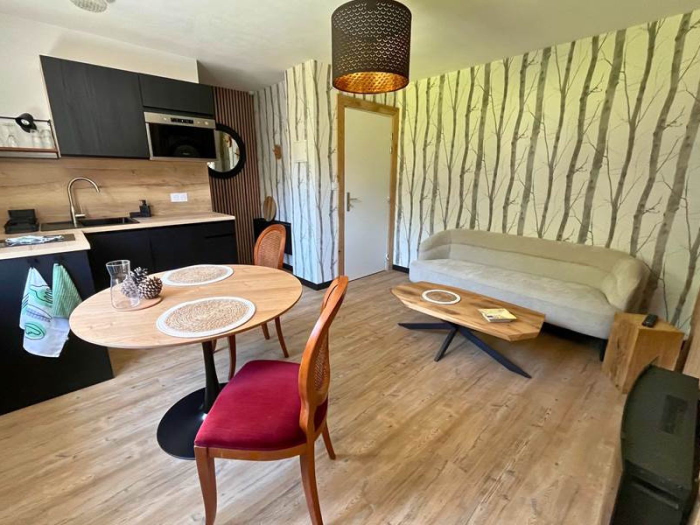 Cuisine design de l'appartement T2 avec mobilier en bois clair, évier noir et équipements modernes.