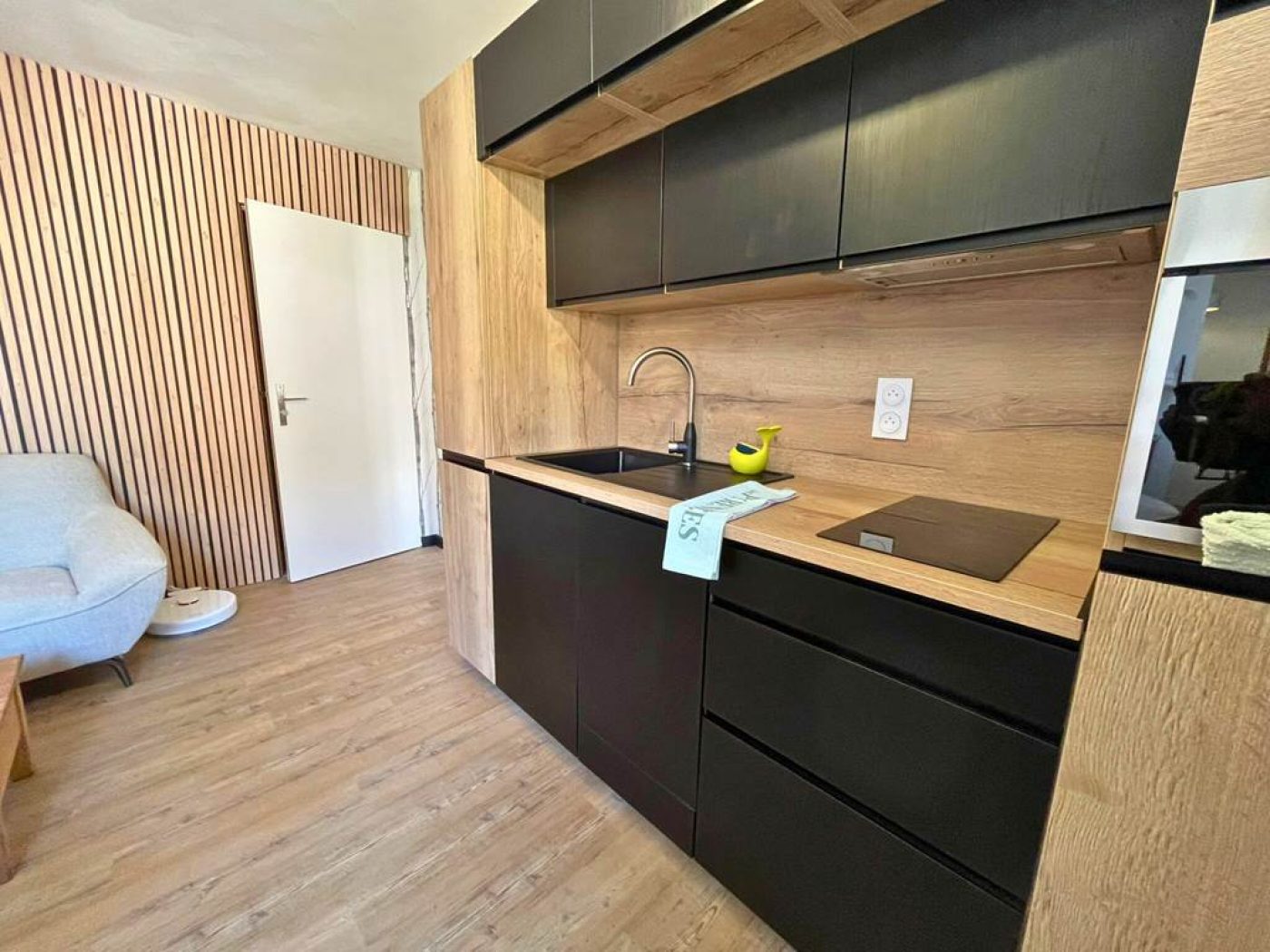 Cuisine équipée moderne de l'appartement T3 avec meubles en bois, évier noir et plan de travail design.