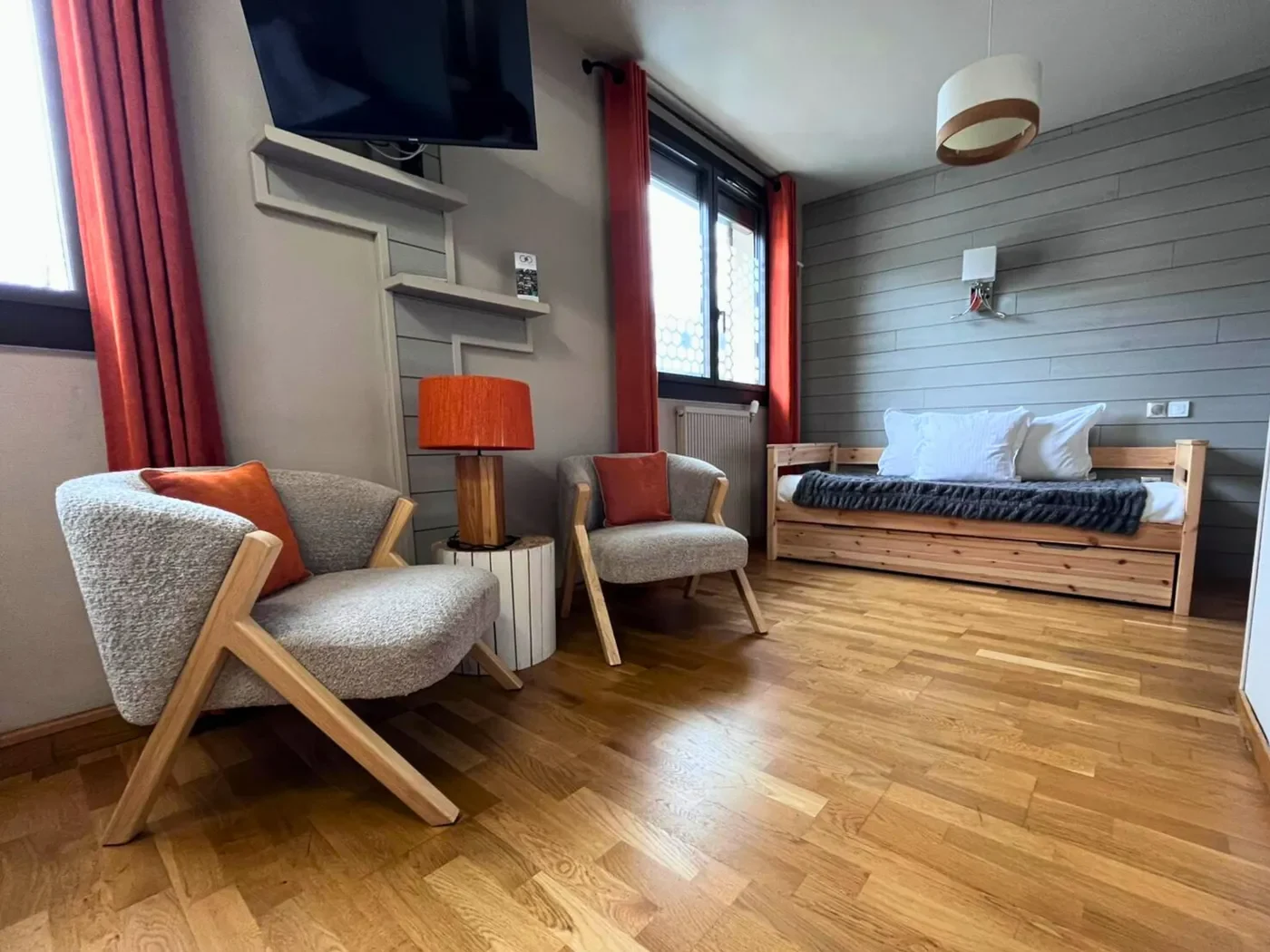 Coin salon de la chambre 11 avec deux fauteuils gris cosy, lampe orange design et tableau d'ours polaire.