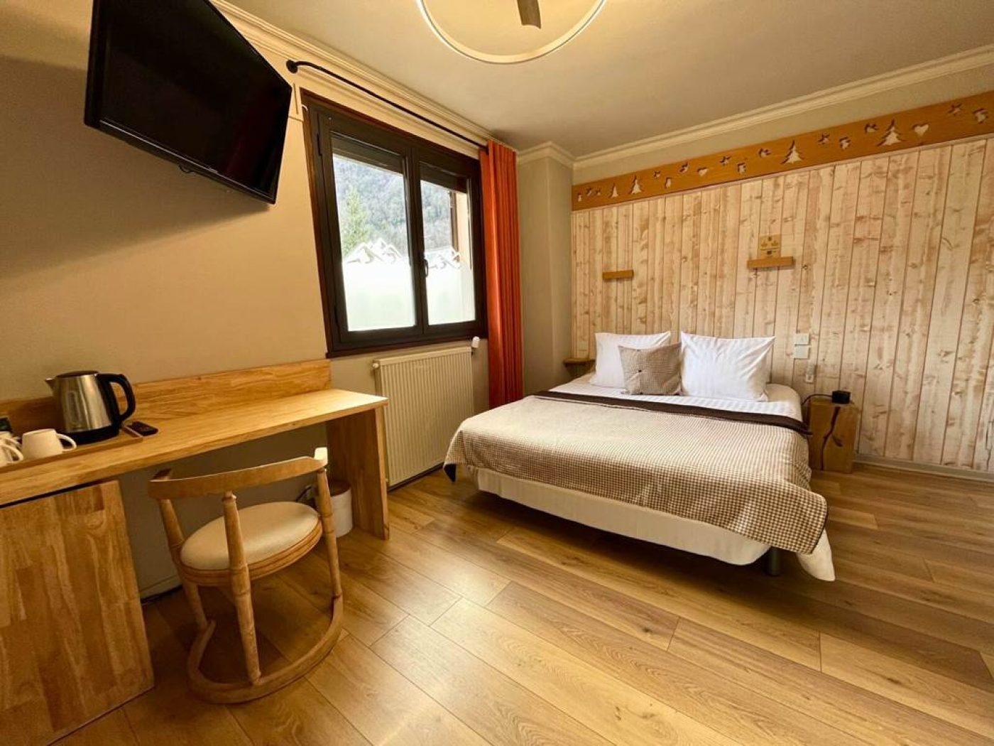 Chambre triple n°7 de l'Hôtel La Rencluse avec lit queen-size, bureau en bois et vue sur les montagnes.