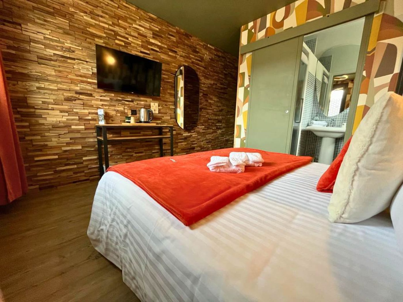 Vue globale de la chambre 10 montrant le lit king-size, le bureau et la porte coulissante verte vers la salle de bain.