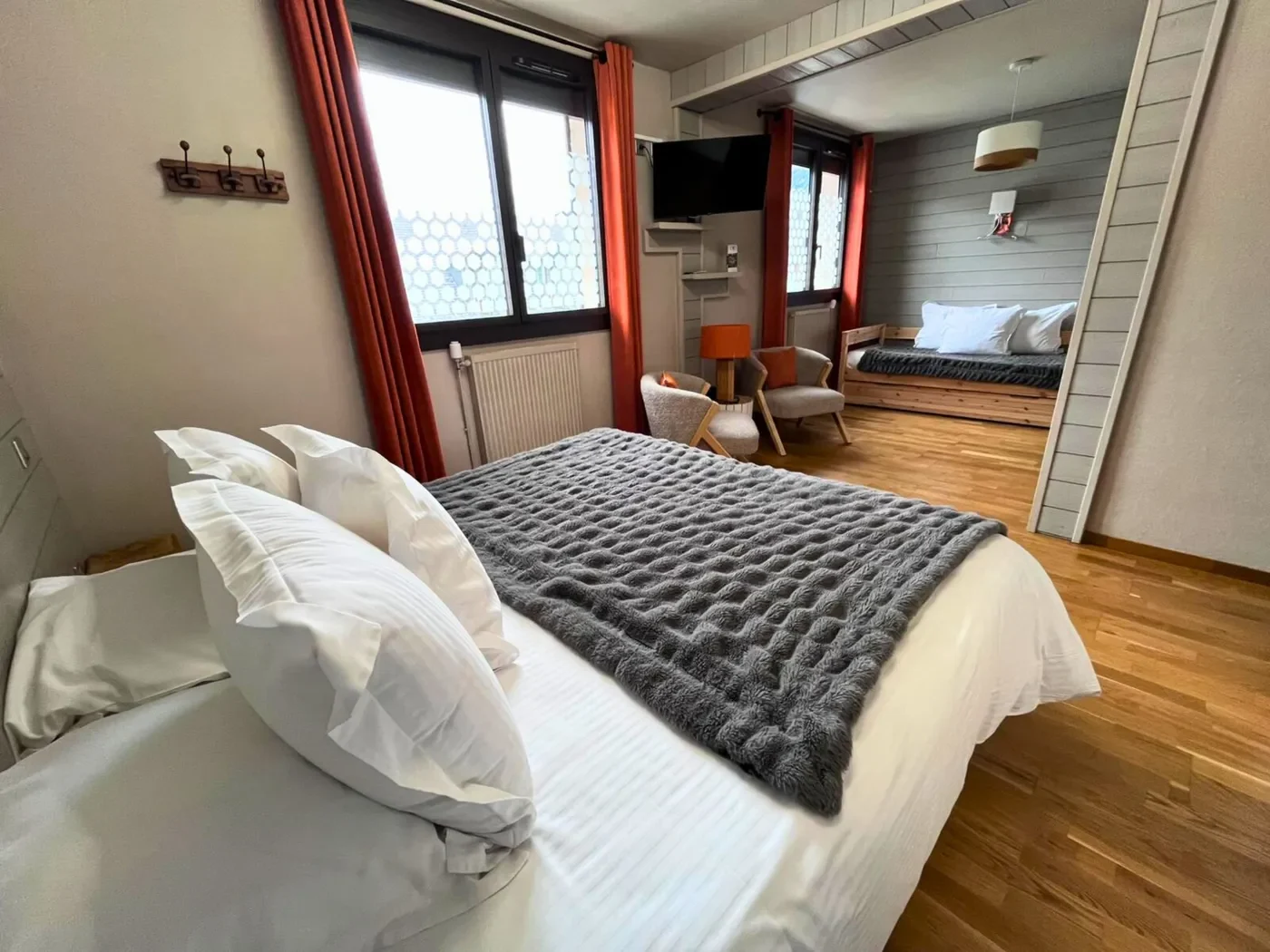 Vue globale de la chambre triple n°11 avec lit queen-size, lit simple au fond et grandes fenêtres lumineuses.