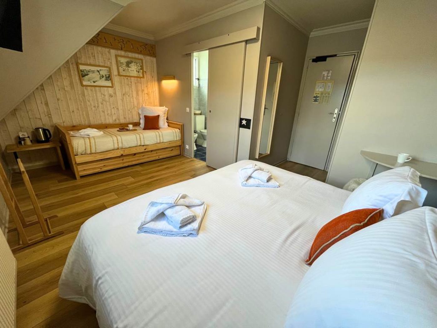 Vue globale de la chambre triple n°14 avec lit queen-size, lit simple sous pente et porte coulissante vers la salle de bain.