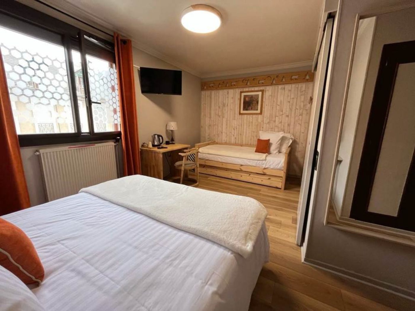 Vue haute du lit queen-size montrant la frise en bois sculpté et le linge de lit blanc immaculé.
