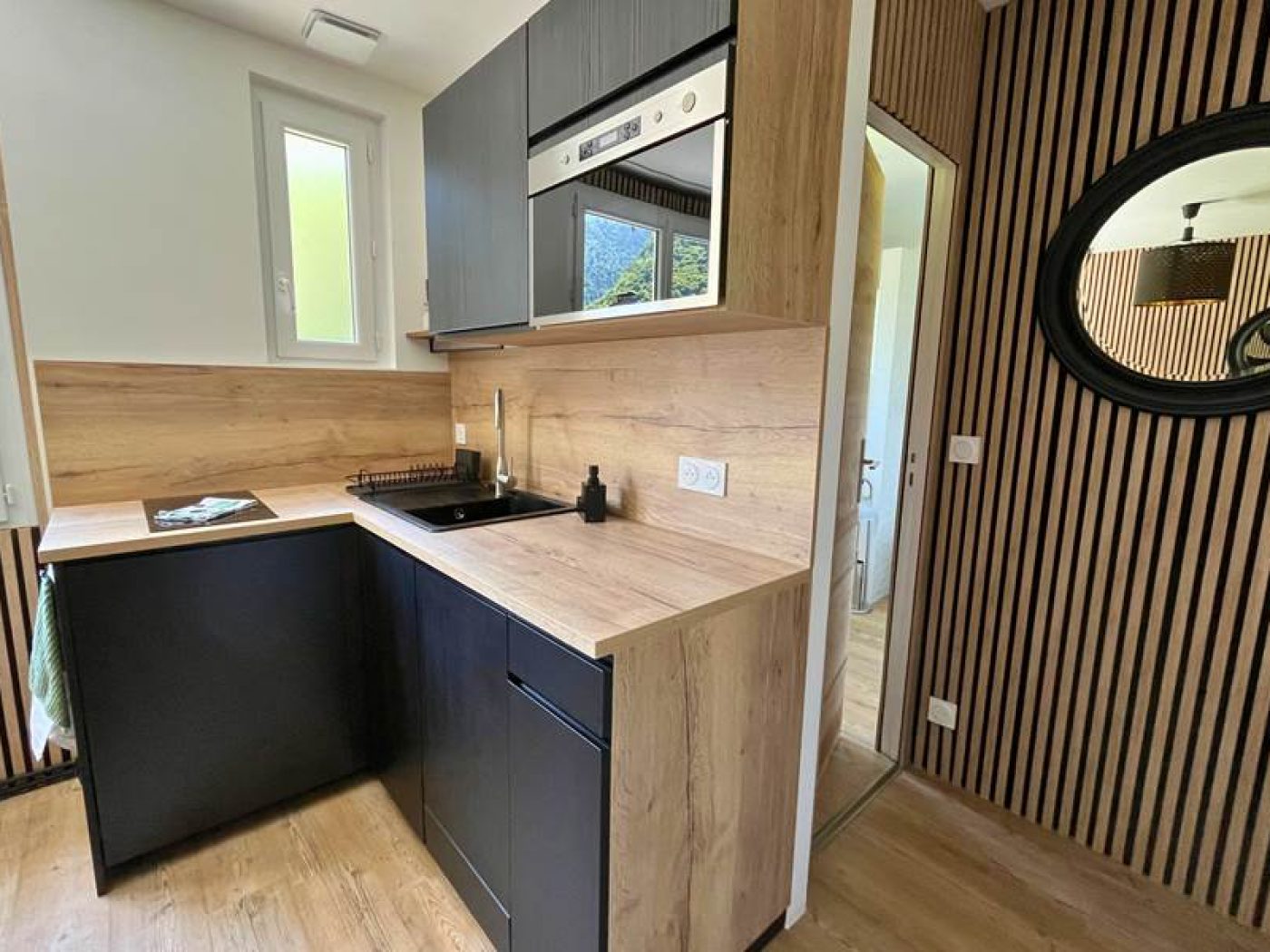 Zoom sur le plan de travail de la kitchenette avec plaques à induction, bouilloire et évier design.