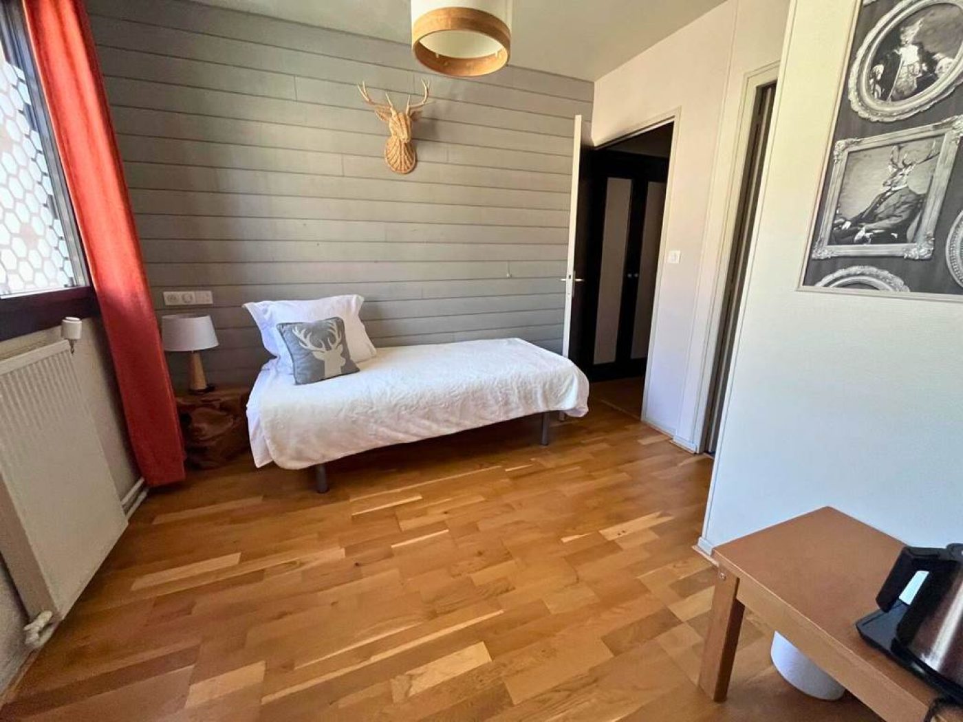 Vue large de l'espace lit simple dans la chambre triple n°4 avec trophée de cerf en osier et coin thé.