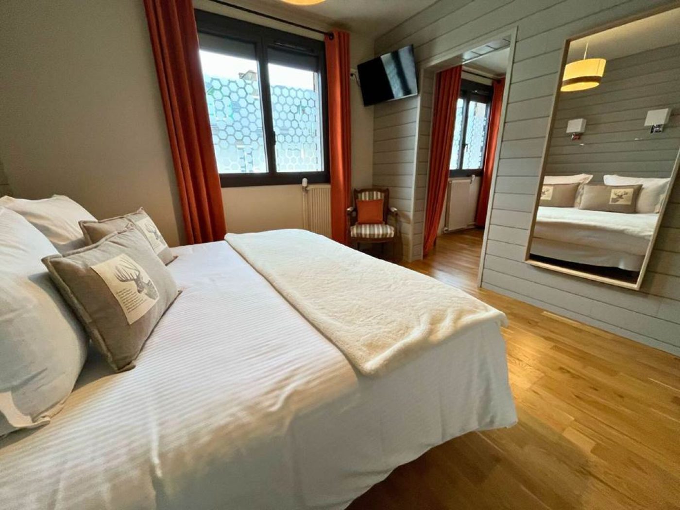 Vue latérale montrant le grand miroir de pied reflétant la literie king-size de la chambre triple.
