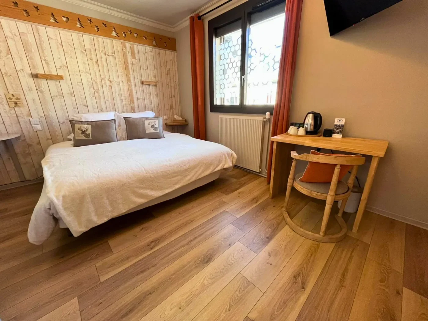 Vue du lit queen-size de la chambre 6 avec le sol en parquet et le placard intégré.