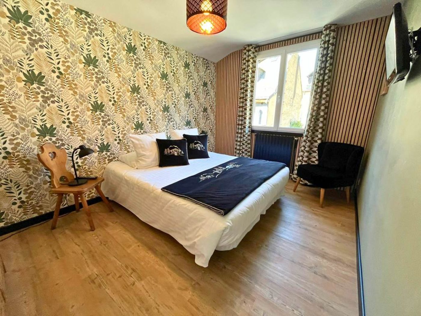 Zoom sur le lit double avec linge de lit blanc immaculé et mur en bois clair dans la chambre du T3.