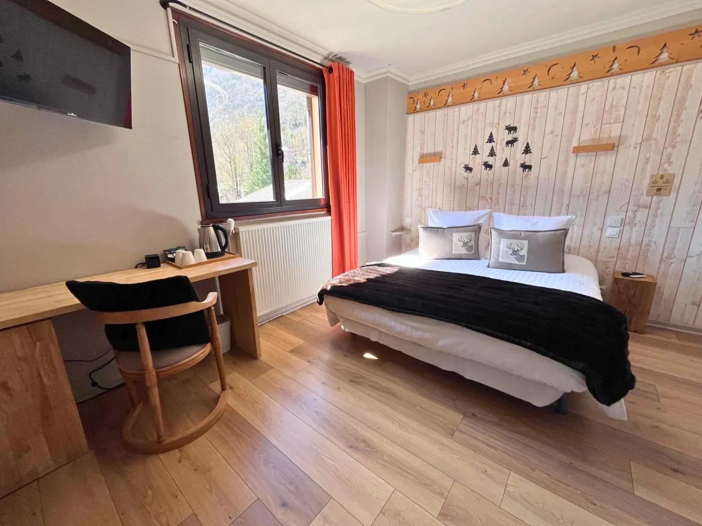 Lit double king-size en chambre 15 avec bureau, chaise design et vue sur Luchon par la fenêtre.