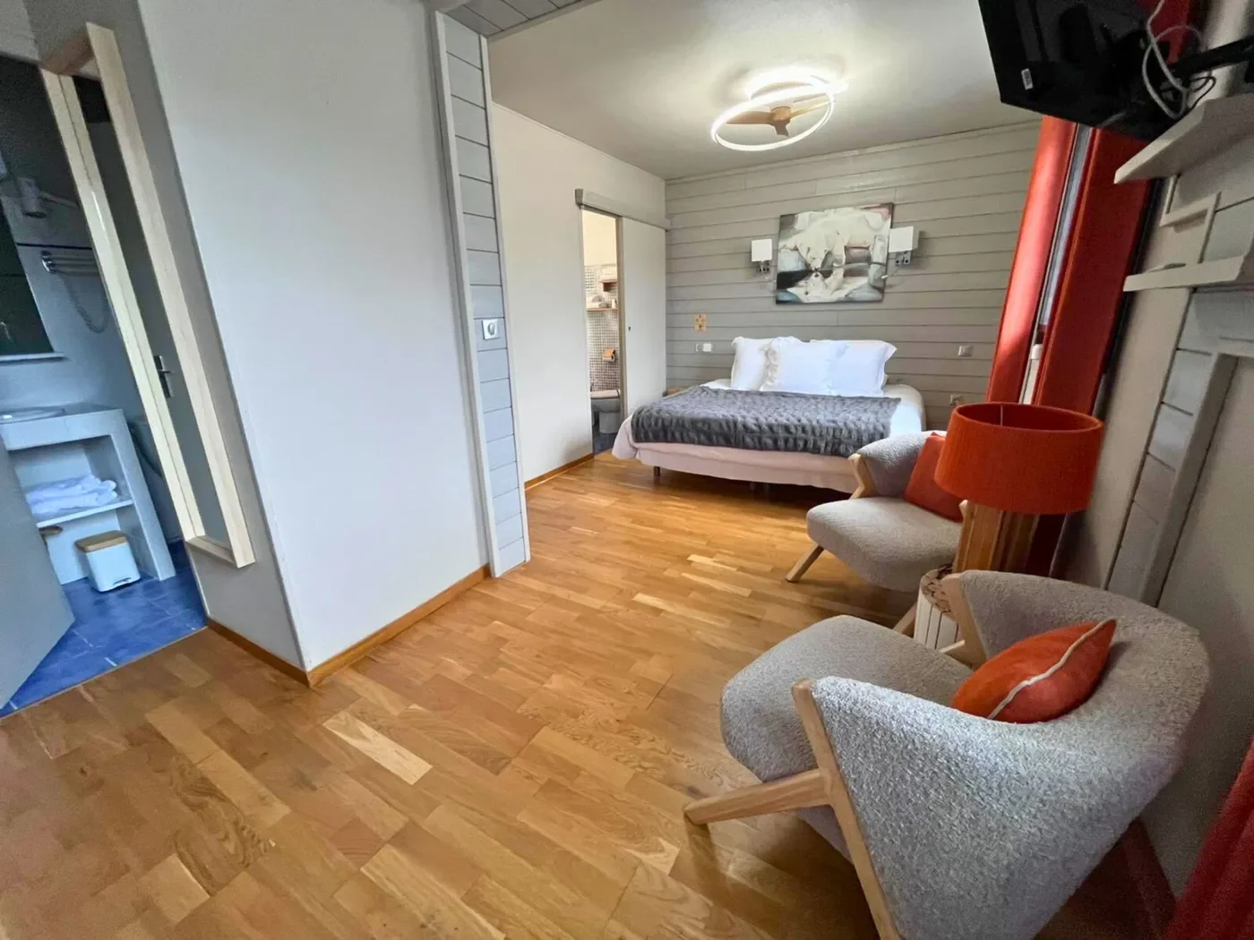 Vue perspective de la chambre 11 montrant le lit king-size, le coin salon et l'accès à l'une des deux salles de bain.