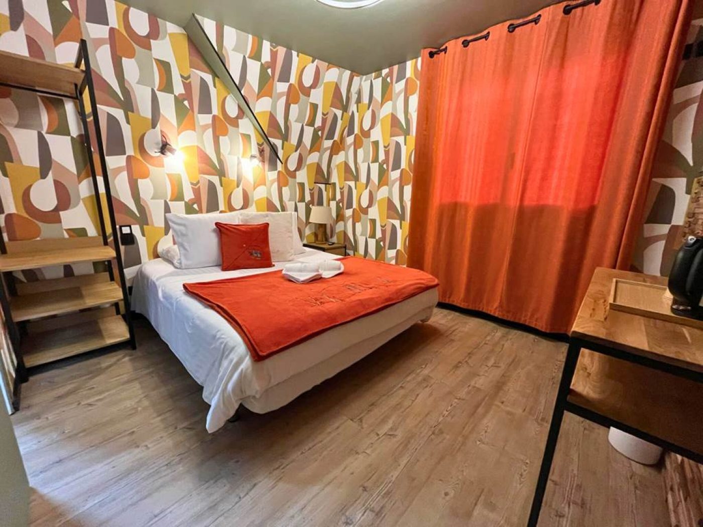 Perspective du lit queen-size avec rideaux orange vif et papier peint géométrique en chambre 10.