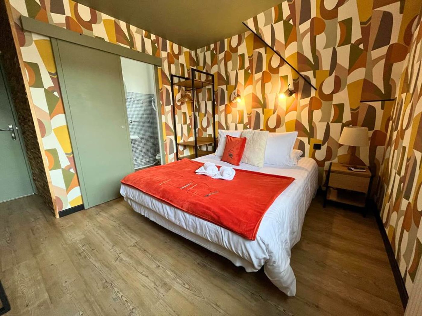 Vue rapprochée du lit de la chambre 10 ouvrant sur la salle de bain privative en mosaïque bleue.