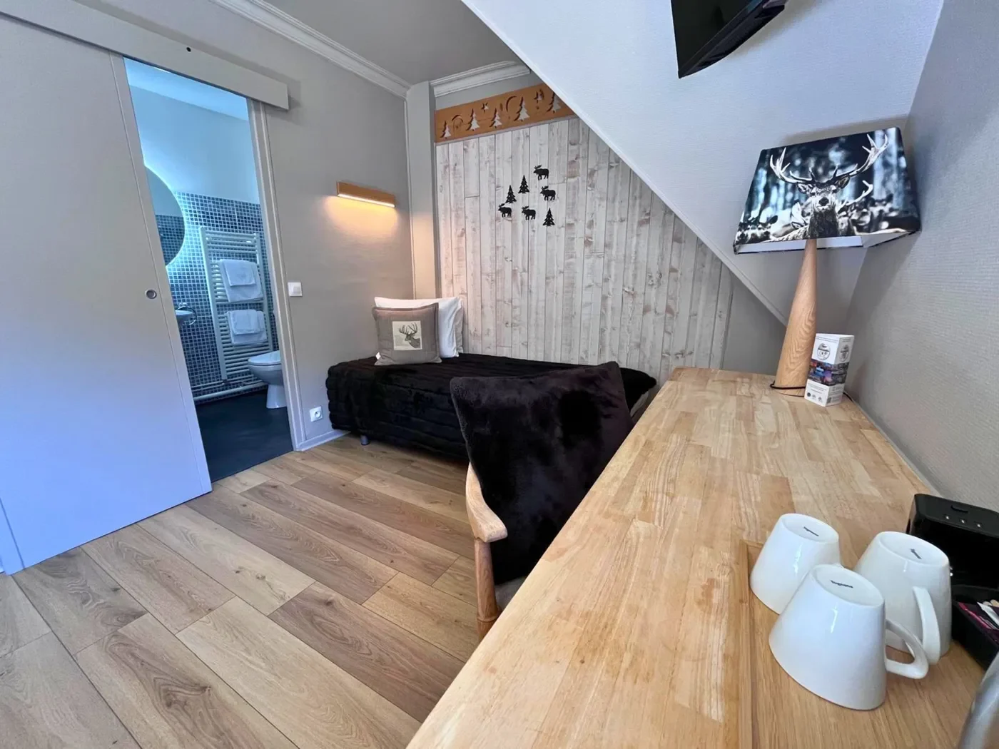 Coin nuit indépendant avec lit simple, bureau en bois massif et lampe design cerf dans la chambre 15.