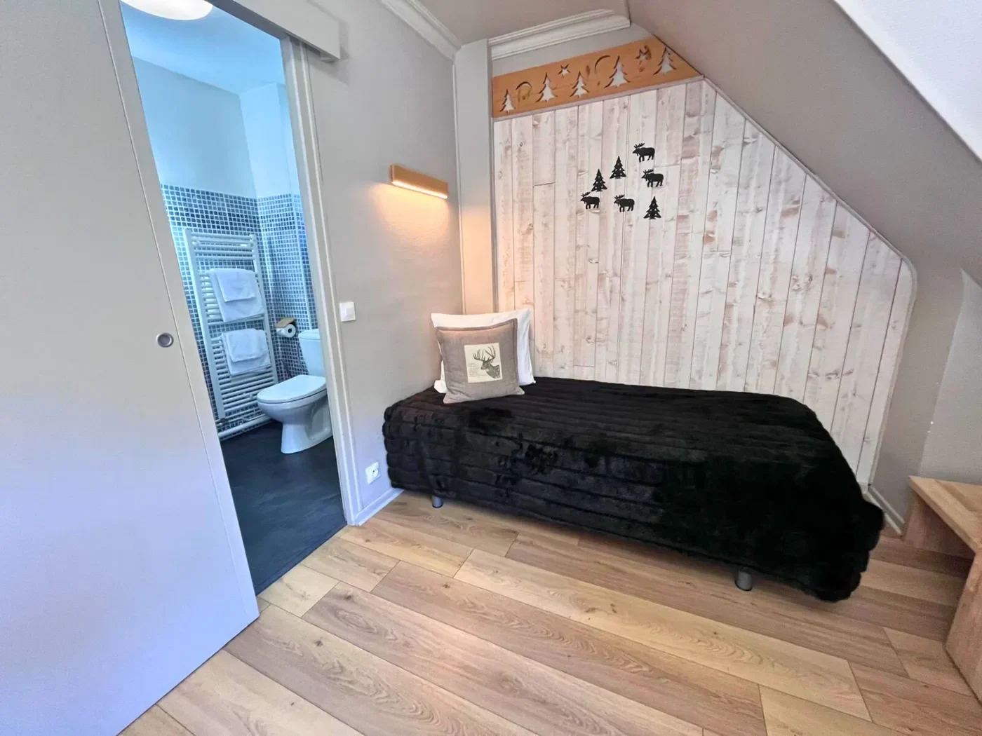 Zoom sur le lit simple 90x200 et l'entrée de la salle de bain de la chambre triple 15.