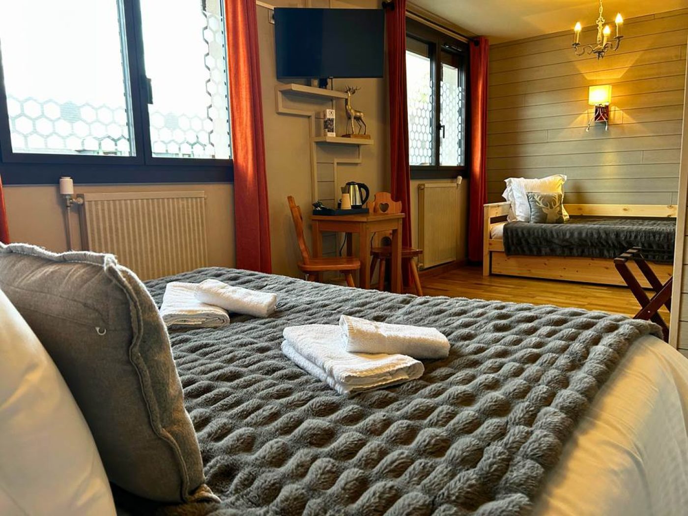 Détail du lit king-size avec linge de lit gris gaufré, télévision écran plat et vue vers la fenêtre.