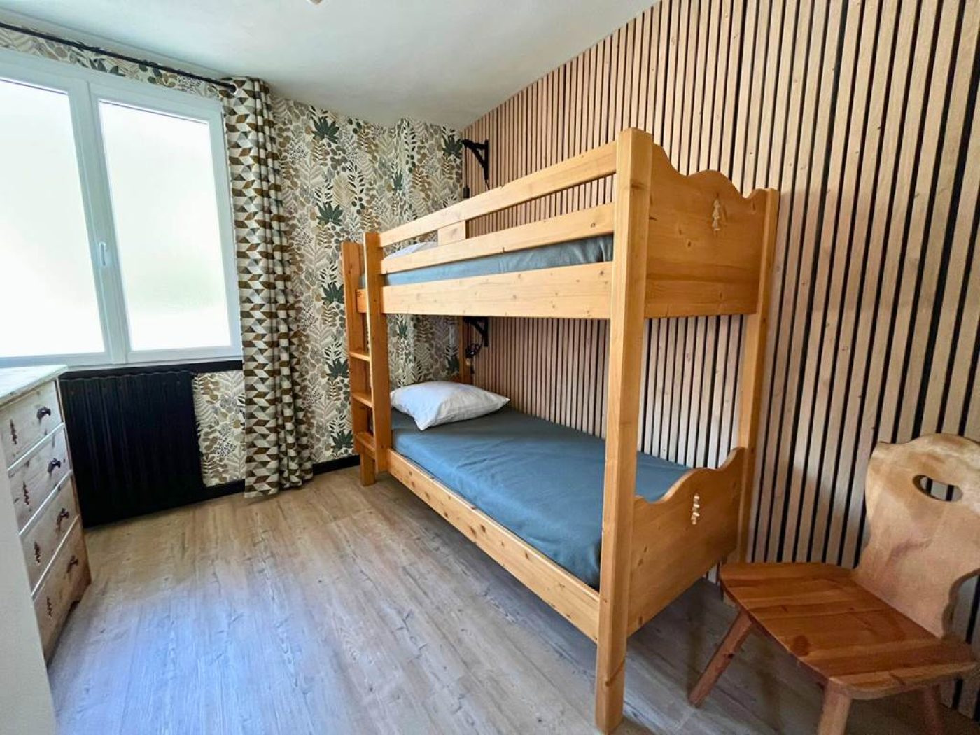 Seconde chambre de l'appartement T3 avec deux lits superposés en bois, fenêtre lumineuse et bureau.