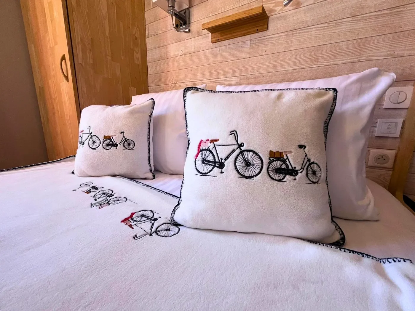 Zoom sur les oreillers moelleux et le linge de lit blanc immaculé de la chambre double n°8, avec mur en bois.