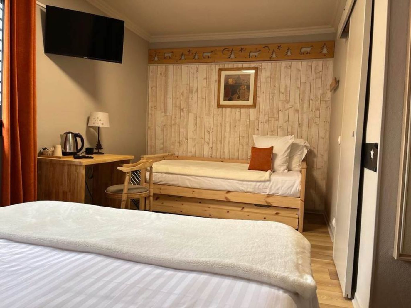 Coin nuit avec lit simple 90x200, frise décorative sapins et bureau en bois massif dans la chambre 6.