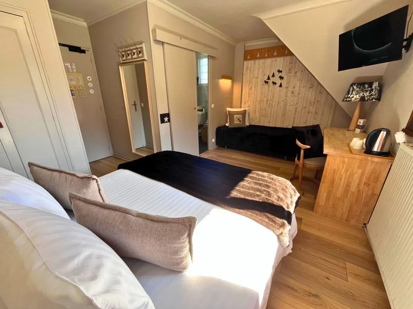 Vue d'ensemble de la chambre triple n°15 avec lit queen-size, lit simple sous pente et bureau en bois.