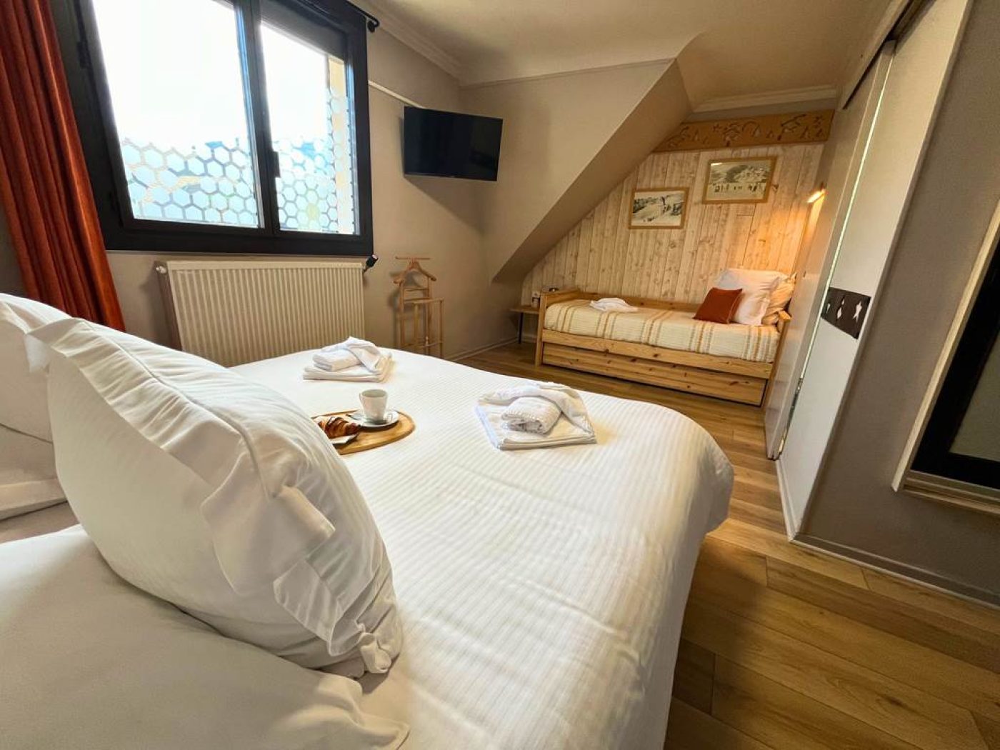 Vue en profondeur depuis le lit double montrant le lit simple, la fenêtre et le plateau de courtoisie.