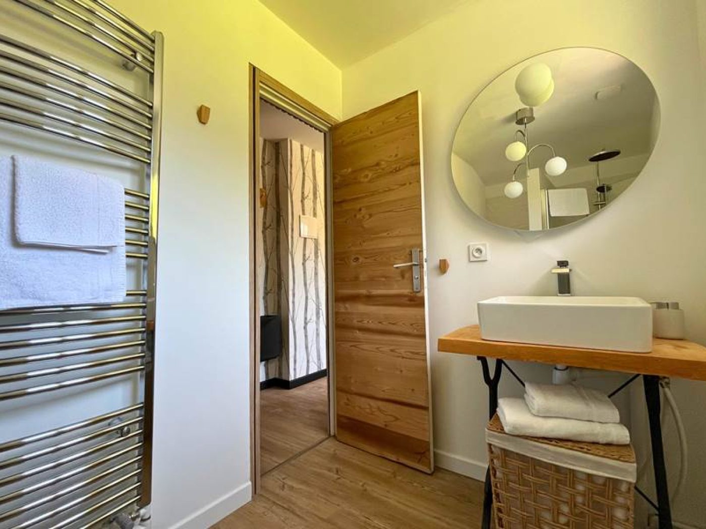 Salle de bain moderne de l'appartement T2 avec vasque blanche suspendue et miroir lumineux.