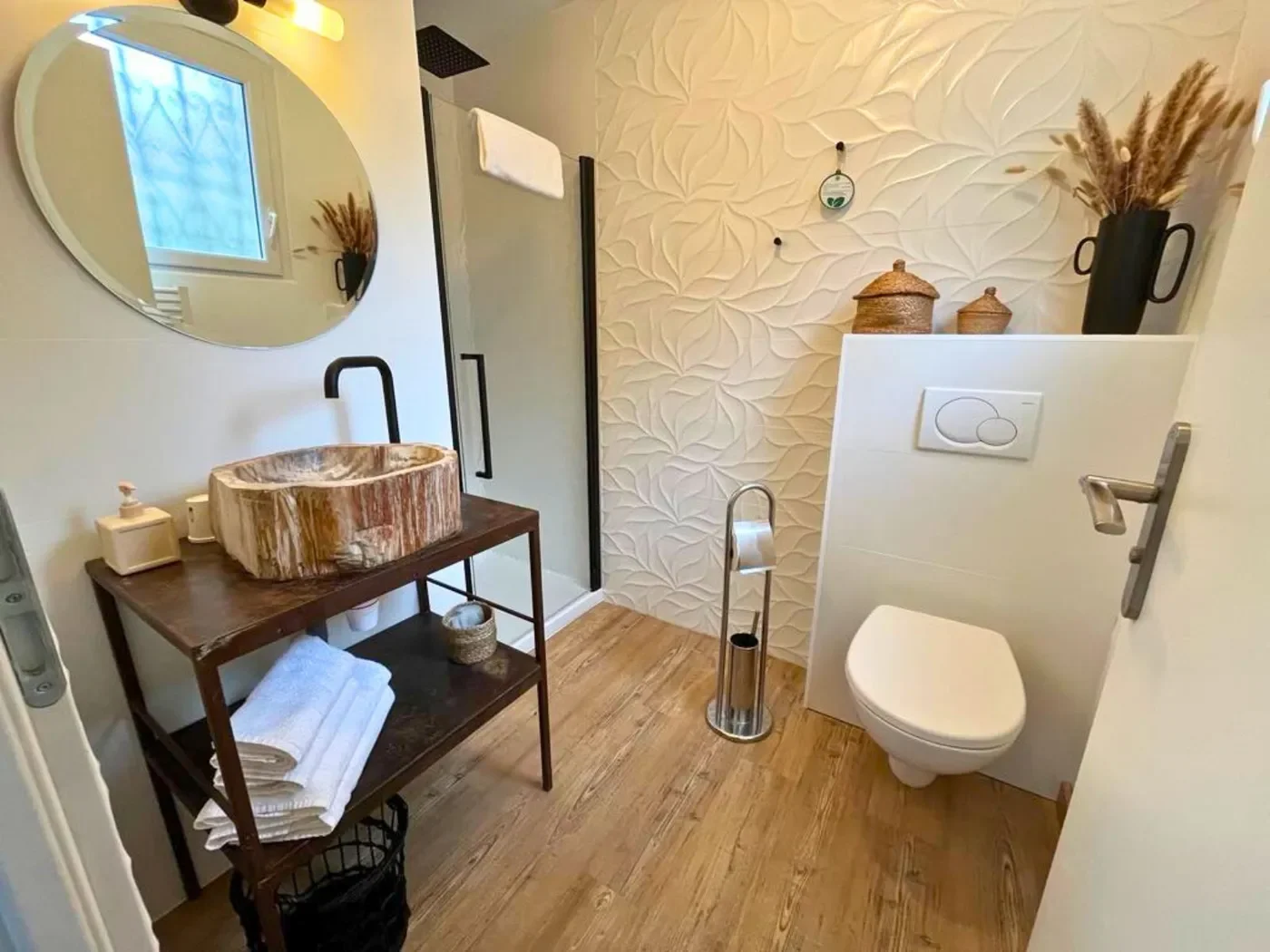 Salle de bain moderne du studio annexe avec vasque en pierre fossilisée, miroir rétro-éclairé et douche à l'italienne.